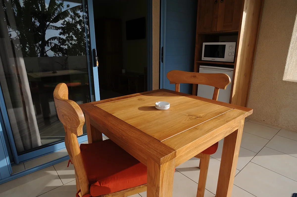 La cuisine d'une terrasse, avec sa table et ses chaises en bois