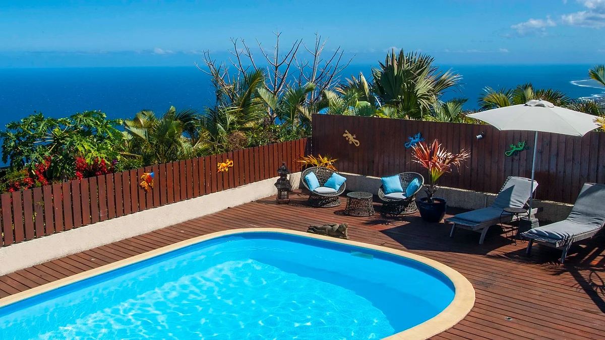 La piscine chauffée et sa terrasse en bois, avec la baie de Saint-Leu en contrebas